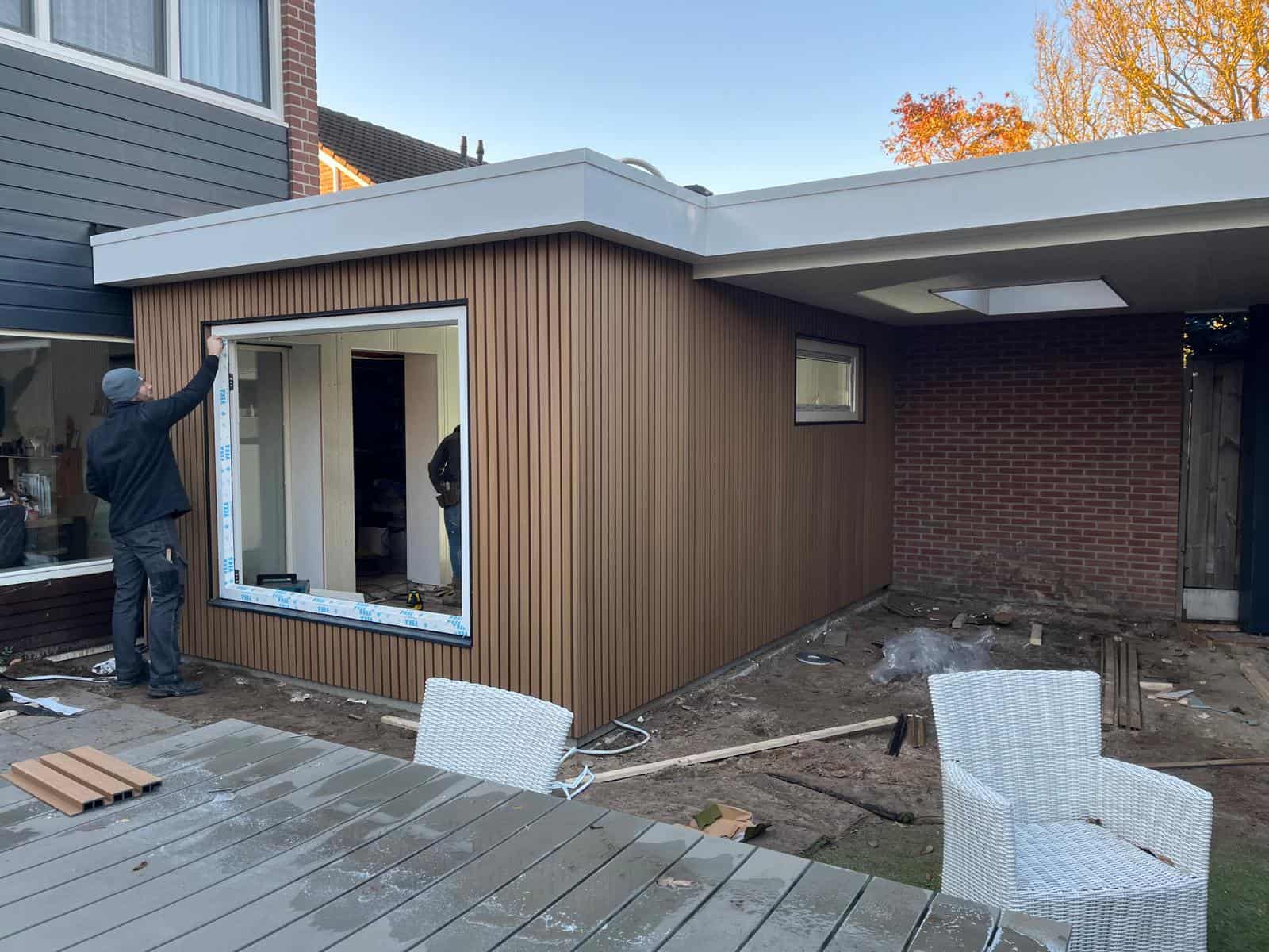 modern huisrenovatie met houten gevelbekleding en grote ramen, zonsopkomst in de achtergrond.