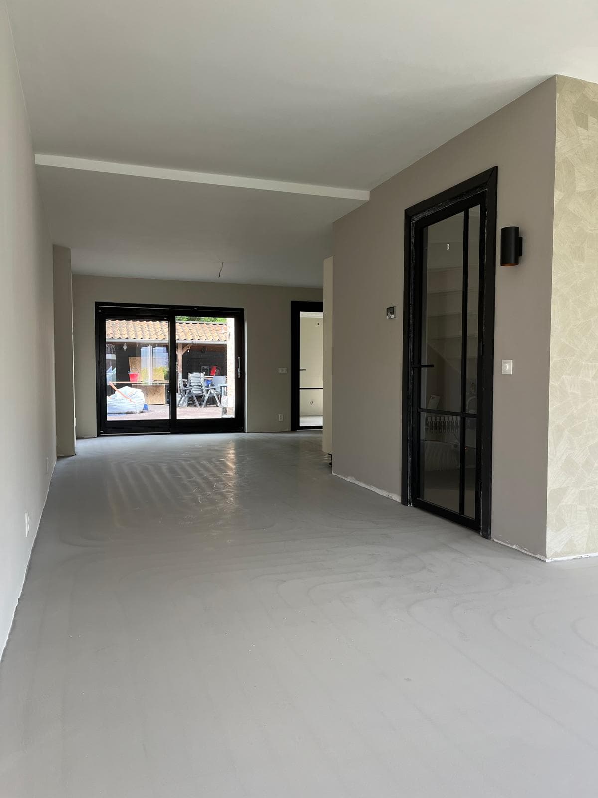 modern woonhuis interieur met grote raampartijen en donkere deuren.