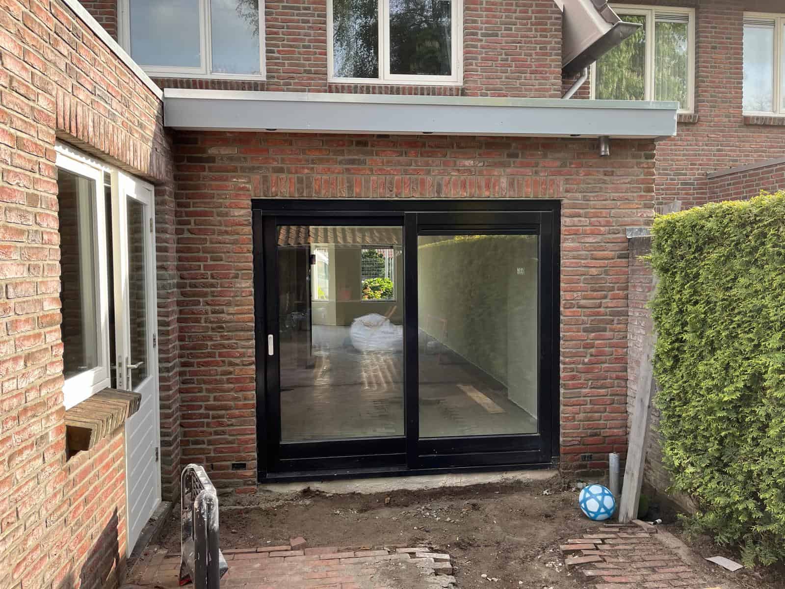 modern terrasdeur met zwart frame en grote glazen panelen, perfect voor tuintransformatie en woningverbetering.